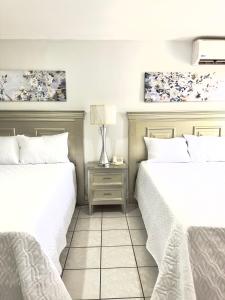 two beds in a bedroom with white sheets and a table at Gran Hotel Paris in La Ceiba