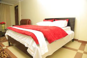 a bedroom with a bed with a red blanket on it at AIRPORT HOTEL Entebbe in Entebbe