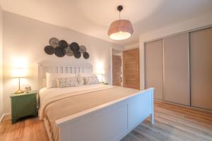 um quarto com uma grande cama branca e 2 candeeiros em Tranquil Retreats in the Scenic Cotswolds em Stroud