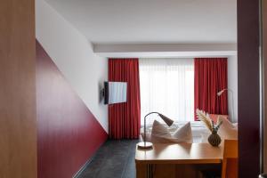 um quarto de hotel com uma cama e uma parede vermelha em Mein SchlossHotel em Heusenstamm