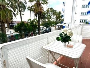 una mesa blanca con un jarrón de flores en el balcón en Sitges Seafront Ribera Apartment, en Sitges