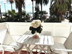 a white table and chairs with a vase of flowers at Sitges Seafront Ribera Apartment in Sitges