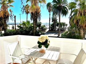 シッチェスにあるSitges Seafront Ribera Apartmentのヤシの木が茂るバルコニー(テーブル、椅子2脚付)