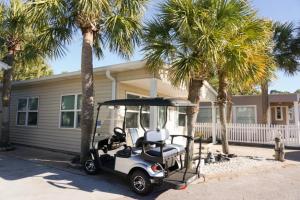 a golf cart parked in front of a house with palm trees at Venture Out 79 Gulf Loop Comes With Golf Cart in Panama City Beach