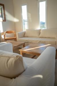 a living room with white couches and a wooden table at La Posta de los Toldos in Perito Moreno
