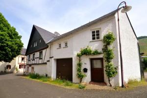 a white building with a black roof and a garage at Friends&Family Veldenz L in Veldenz