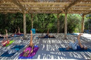un grupo de personas haciendo yoga bajo una pérgola en Les villas de Bagheera, oasis naturiste, en Linguizzetta