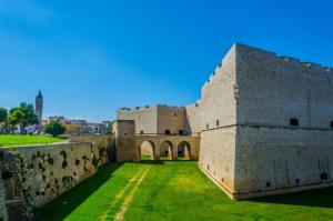 an old castle with a green field in front of it at Casa Brezza marina in Barletta