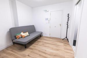 ein graues Sofa in einem Zimmer mit Holzböden in der Unterkunft Estudio-oficina moderno, centro de Jaén in Jaén