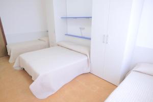 um quarto branco com 2 camas e um armário em Vistamare Apartments em Jesolo