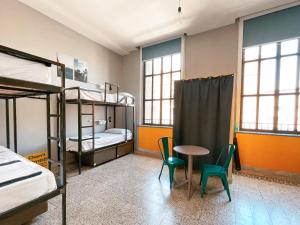 ナポリにあるOstello Bello Napoliの二段ベッド、テーブル、椅子が備わる客室です。