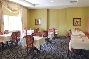 un comedor con mesas y sillas blancas en Monte Carlo Inn & Suites Downtown Markham en Markham