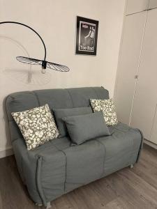 a gray couch with pillows in a living room at Mytripinparis - Sablons in Neuilly-sur-Seine