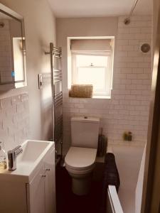 uma casa de banho com um WC, um lavatório e uma janela em The Old Post Office Studio Apartment in a Beautiful Cotswold Village em Cirencester