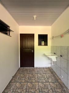 baño con puerta negra y lavamanos en Quitinete Vó Ana, en Penha
