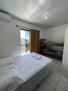 1 dormitorio con cama blanca y balcón en Quitinete Vó Ana, en Penha