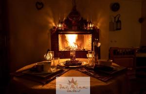 a dining room table with a fireplace in the background at Dar Ahlam Dades in Aït Ouaddar