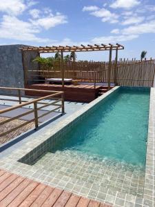 a wooden deck with a pergola over the water at Pousada Baobá in Jericoacoara