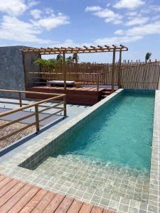 um deque de madeira com uma pérgola sobre a água em Pousada Baobá em Jericoacoara