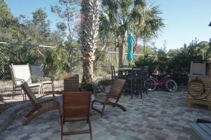 a patio with chairs and tables and a palm tree at Venture Out 476 Marlin Dr Comes WITH GOLF CART in Panama City Beach