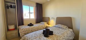 a bedroom with two beds and a window at Homes of Spain, Apartamentos Paraiso Vera Playa, Ed Tahiti, Atico B de 2 dormitorios con piscina privada en solárium y barbacoa, pie de playa in Playas de Vera +41 photos