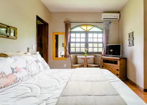um quarto com uma grande cama branca e uma televisão em The Cats' House em Florianópolis