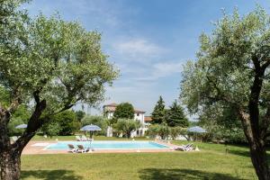una piscina con sombrillas en un parque con árboles en Agriturismo Colombare Teboi Trilo, en Lazise