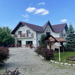 ein großes weißes Haus mit einer Veranda und einer Auffahrt in der Unterkunft Casa Nicholas in Zărneşti