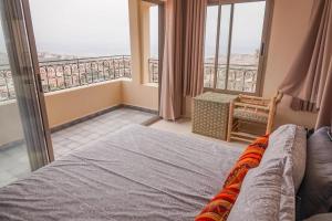 a bedroom with a bed and a balcony at SurfAppart Morocco in Tamraght Ouzdar