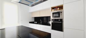 een keuken met witte kasten en een zwart apparaat bij Amanecer 7 Alicante in Orihuela
