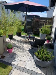 een patio met een parasol, stoelen en potplanten bij Work and Stay Erlensee in Erlensee