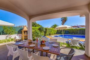 um pátio com uma mesa e cadeiras e uma piscina em Villa Bolina by Villa Plus em Albufeira