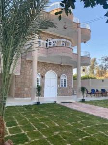 a large house with a balcony and a yard at Nile Palace Guest House in Luxor
