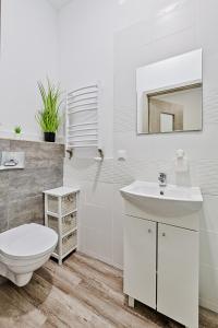 ein weißes Bad mit einem WC und einem Waschbecken in der Unterkunft DeLux9 in Łódź