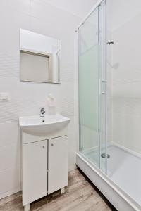 ein weißes Bad mit einem Waschbecken und einer Dusche in der Unterkunft DeLux9 in Łódź