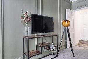 een televisie op een stand met een vaas van bloemen bij Deluxe Large Three Room Apartment by Southend Stays in Southend-on-Sea