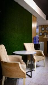 2 sillas, una mesa y una pared verde en Apart Hotel en Tashkent