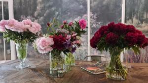 trois vases remplis de fleurs sur une table en bois dans l'établissement mi casa de buenos aires, à Buenos Aires