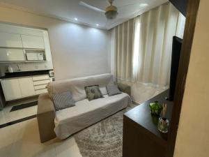 een woonkamer met een witte bank en een keuken bij Água Campos in Campos dos Goytacazes