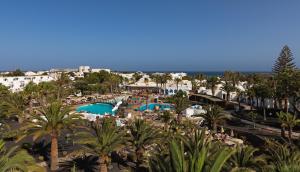 a view of the pool at a resort with palm trees at H10 Suites Lanzarote Gardens in Costa Teguise