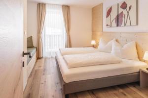 a bedroom with a large white bed in front of a window at Schöpfer Hof - Urlaub beim Biobauer in Rasun di Sopra