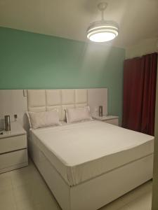 Cama blanca grande en habitación con cortina roja en SUITES-HOME, CIDADELA, en Praia