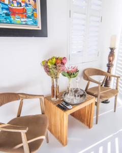 a table with two chairs and vases of flowers on it at Le Grenier Luxury Loft in Franschhoek