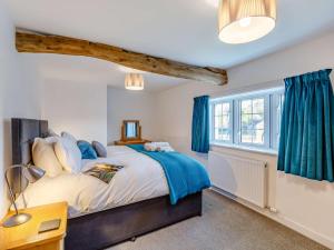 a bedroom with a bed with blue curtains and a window at 3 Bed in Caldbeck 86087 in Caldbeck