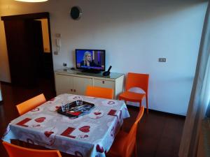 a room with a table with orange chairs and a television at Garden alle barche - Cinzia 5 in Calceranica al Lago