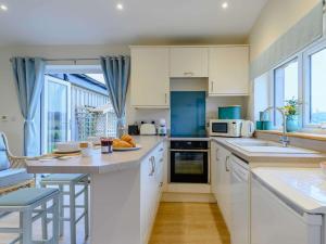 a kitchen with white cabinets and a large window at 1 bed property in Sherborne 86426 in South Cadbury