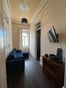 sala de estar con sofá azul y TV en Casa Arte Nova do Rossio, en Aveiro