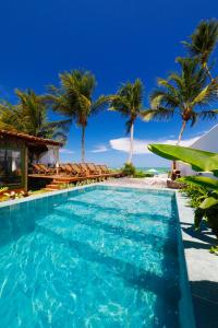 a swimming pool with palm trees and the ocean at Pousada Rota Ecológica in Pôrto de Pedras +89 photos