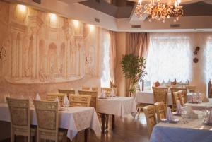 a dining room with tables and chairs and a chandelier at Veles Hotel in Dnipro