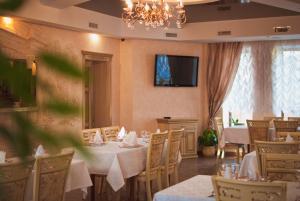 a dining room with tables and chairs and a television at Veles Hotel in Dnipro